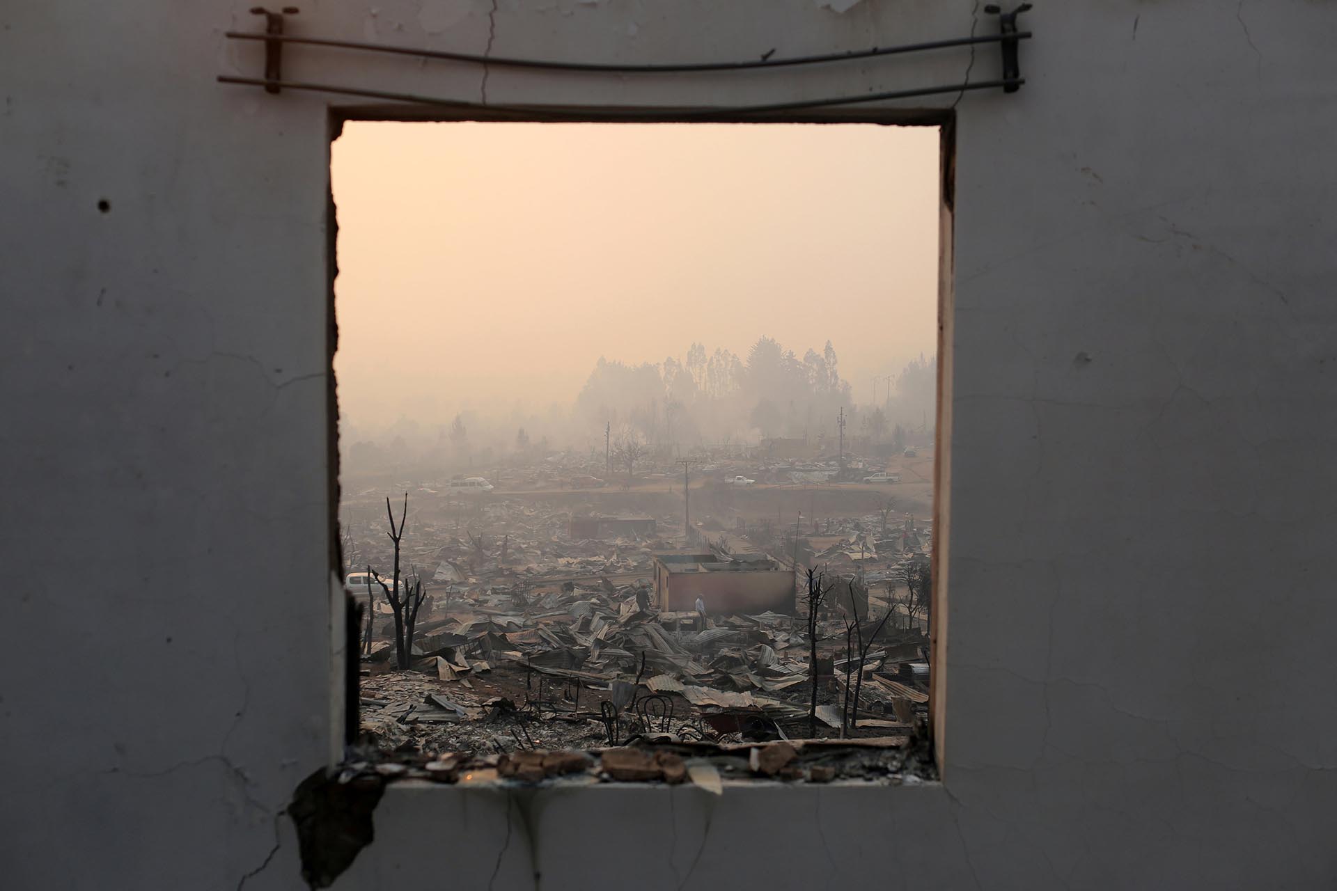 The remains of burnt houses are seen through the window of a destroyed house as the worst wildfires in Chile's modern history ravage wide swaths of the country's central-south regions, in Santa Olga, Chile January 26, 2017. REUTERS/Pablo Sanhueza EDITORIAL USE ONLY. NO RESALES. NO ARCHIVE. TPX IMAGES OF THE DAY